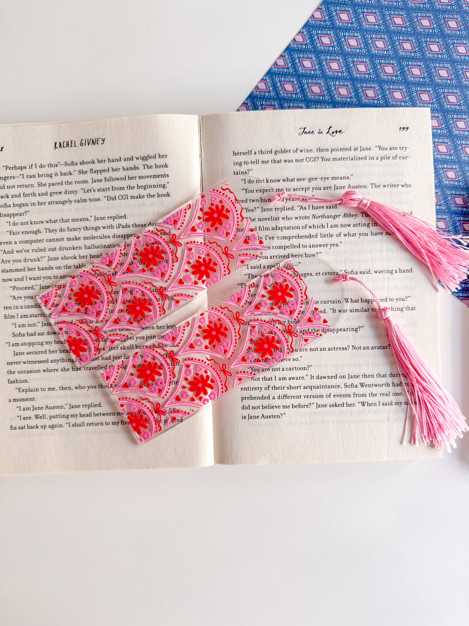 Pink and red patterned bookmarks with tassels on an open book